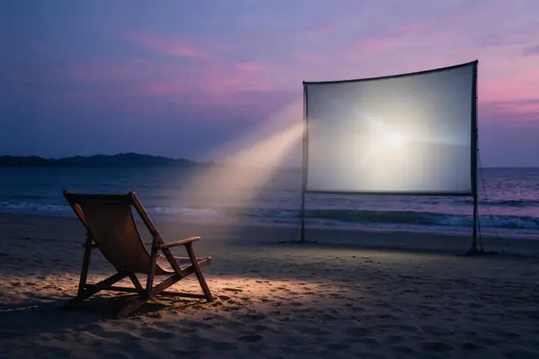 An open-air cinema on the beach at dusk